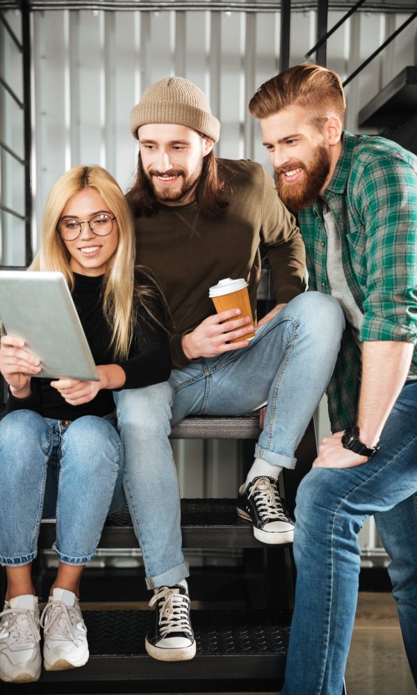 Image of young colleagues in office using tablet computer. Looking aside.